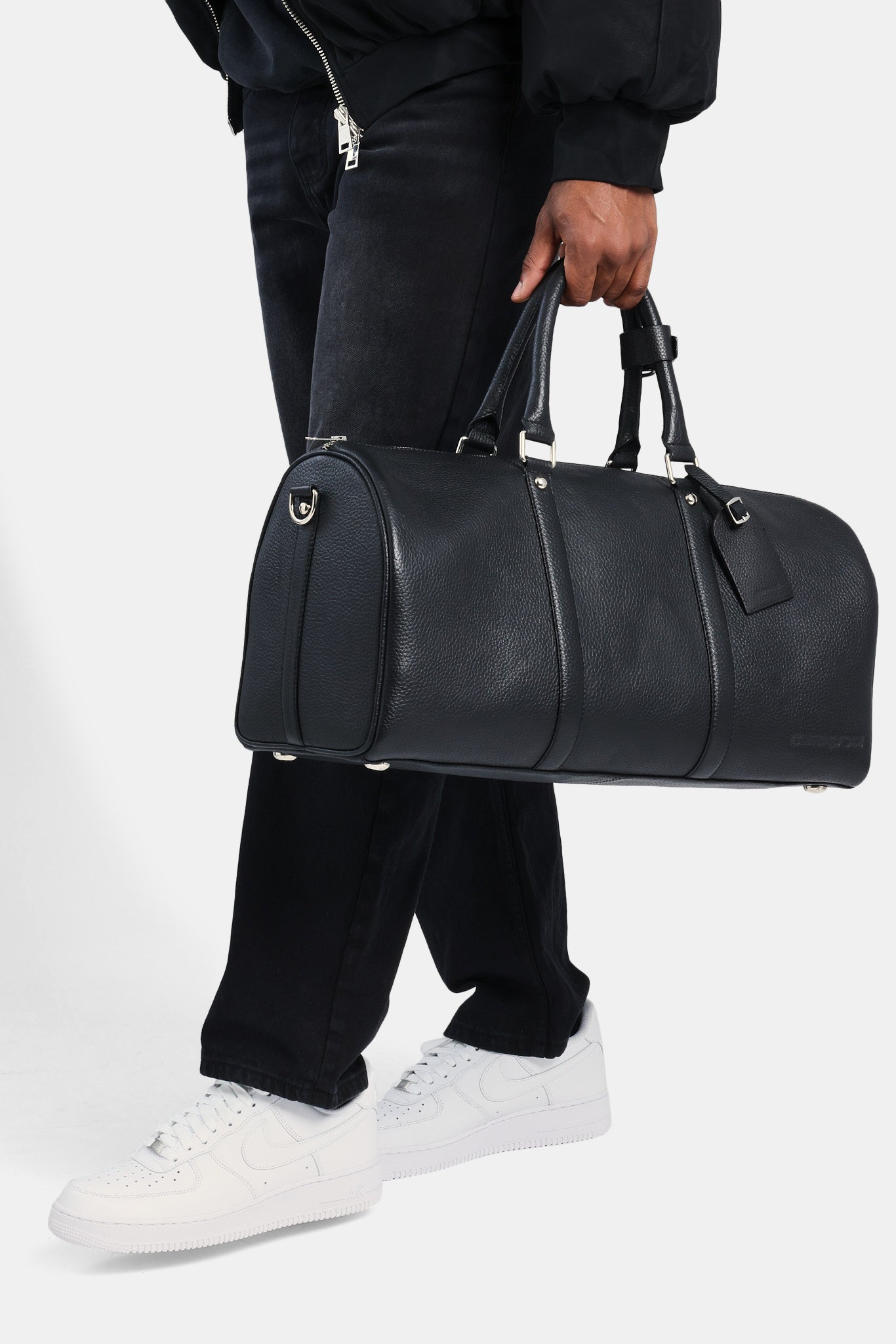 Male model holding the black leather duffle bag